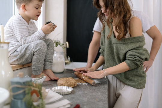 Boy sitting next to mother making cookies in kitchen