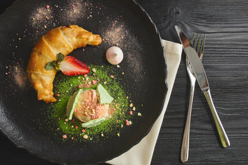 Cherry and apple strudel served with a scoop of vanilla ice cream on a ceramic black plate. view from above. baking dessert