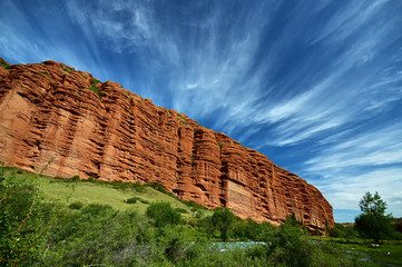 Cirrus clouds over red mountain. Kyrgyzstan