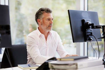Confident Businessman Working On Computer At Desk