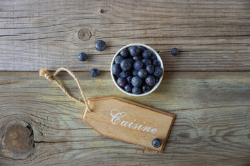 Blueberries in a white bowl with a decorative coisine plate on an old wooden background. Berries. Antioxidants. Vegan food concept. 