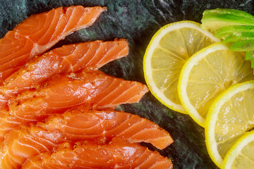 Delicious and healthy homemade salmon slices of avocado and slices of lemon board ready to eat