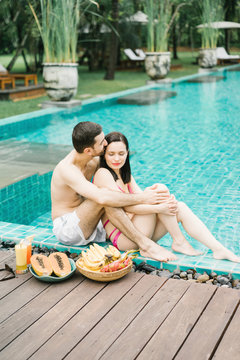 Romantic couple enjoying fruit on poolside