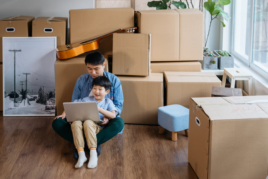 Father and son using computer in new house
