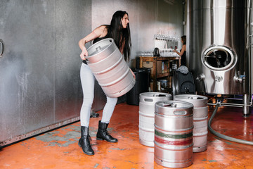 Woman lifting keg in brewery