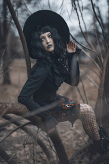 Dark gothic witch in black attire walking in the woods