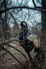 Dark gothic witch in black attire walking in the woods