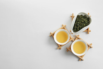 Obraz na płótnie Canvas Cups of Tie Guan Yin and chahe with tea leaves on white background, top view