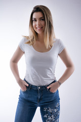 Portrait of beautiful young caucasian student girl with happy teeth smile hair in blue jeans and hands in pockets, looking on camera. Female portrait in studio. Close up