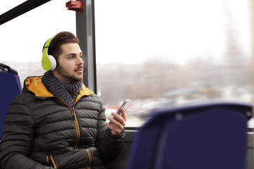 Young man listening to music with headphones in public transport