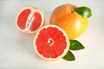 Whole and sliced tasty grapefruits on white background