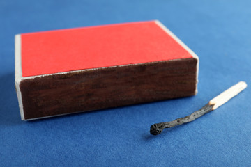 Red box and burnt match on color background, closeup
