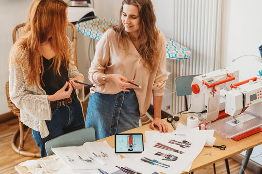 Two young female fashion designers working together at the design studio