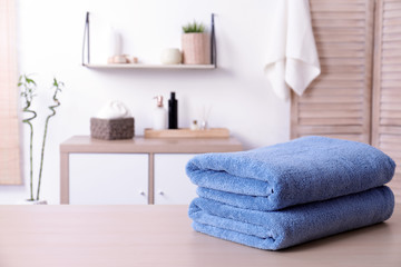 Stack of fresh towels on table in bathroom. Space for text