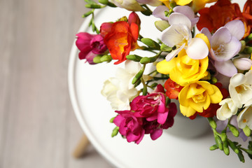 Bouquet of beautiful spring freesia flowers in vase on table. Space for text