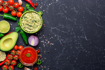 Traditional Mexican Latin American Salsa sauce and Guacamole and ingredients on black stone table. Top view copy space.