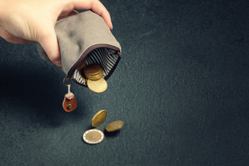 Several coins fall on the table from an empty wallet in a woman's hand, poverty, crisis, bankruptcy...