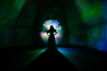 Shadows of a woman in the one room with light painting effect of iridescent colors and rainbows.