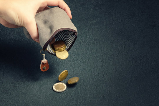 Several coins fall on the table from an empty wallet in a woman's hand, poverty, crisis, bankruptcy and financial problems concept