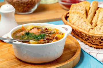 Lentil soup with chicken in a white bowl on a wooden board on a blue table