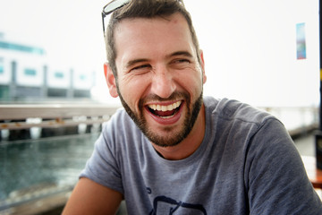 Man sitting in a waterfront cafe laughing