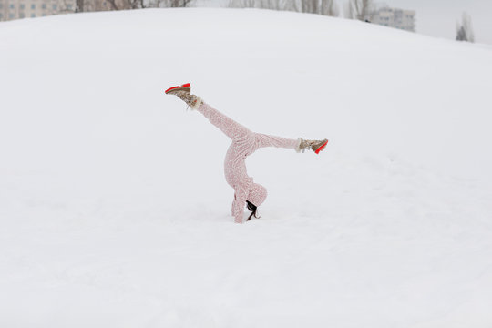 Beautiful woman doing splits in the snow wearing onesie