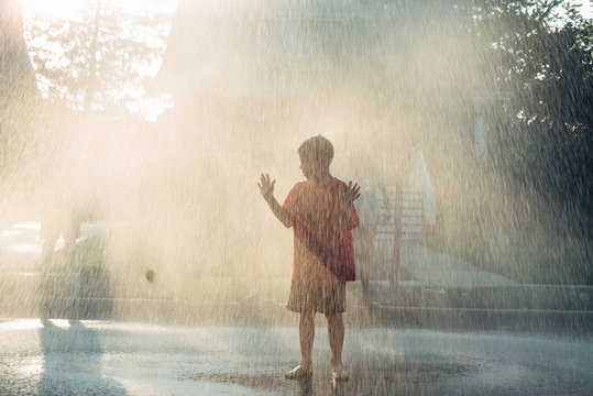 Kid standing in the rain in the middle of the street