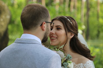 Wedding photo of the bride and groom in a gray-pink color on nature in the forest and rocks.