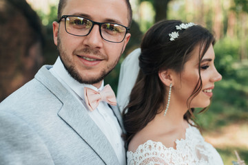 Wedding photo of the bride and groom in a gray-pink color on nature in the forest and rocks.