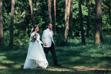 Bride and groom are walking in the woods on their wedding day