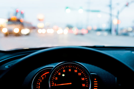 A close-up of a dashboard of a car with a view of traffic through the windshield.