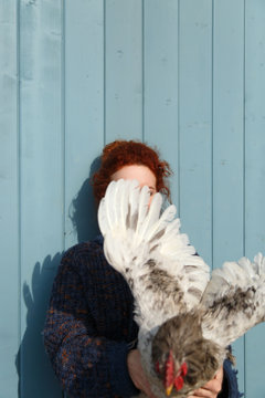 Redhead female holding chicken flapping it wings