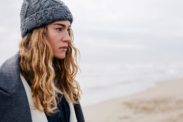 Naklejka premium Portrait of a blonde woman on beach in winter.
