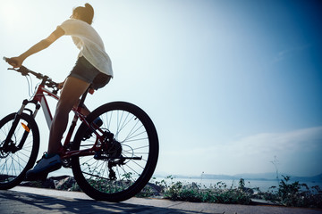 Woman cyclist riding Mountain Bike on sunrise seaside