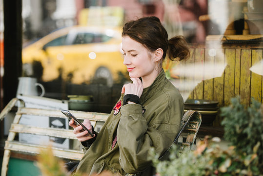 Young smiling woman on phone in city