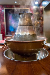 A traditional Chinese hotpot with meat and condiments.