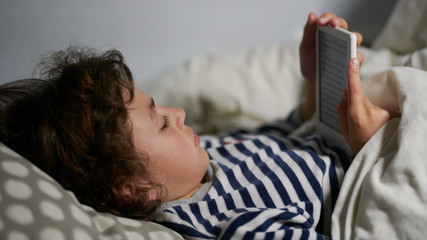 Kid reading kindle in bed