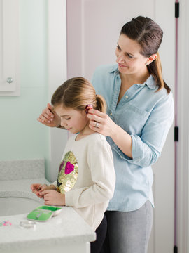 Mother helping her daughter put her hearing aids on