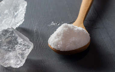 Pure natural white crystal bath or rock salt with food or sea salt in wooden spoon on wooden background