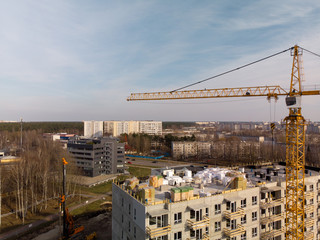 Fototapeta na wymiar Aerial of a building site with a large operating bright yellow crane near a house