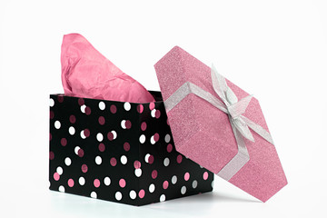 Polka dot gift box with pink tissue paper and glitter lid isolated on white