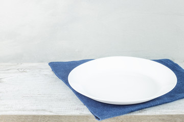 Empty plate on tablecloth on wooden table over grunge background