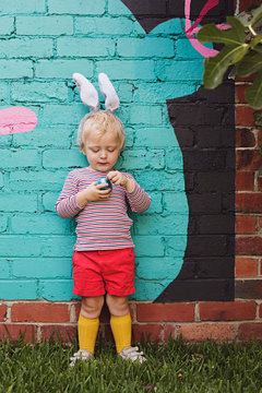 A young toddler boy has a chocolate easter egg hunt in his backyard in Australia
