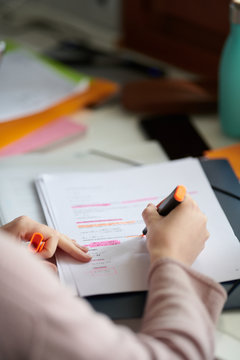 Crop woman highlighting information in document