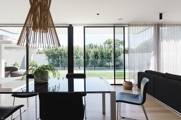 Dining room table with large glass sliding doors looking out on to the backyard and pool