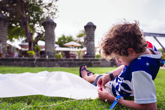 Boy rigging a sail lying on grass beside the pillars of the historic Nelson's dockyard