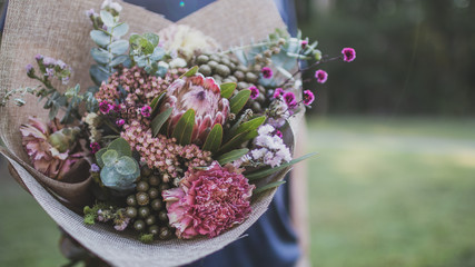 man holding bouquet of Australian native flowers close up in the green garden with copy space