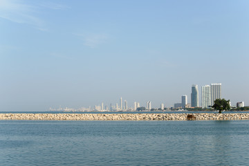 View on Pattaya city and sea from Ban Amphur beach. Buildings on the horizon.
