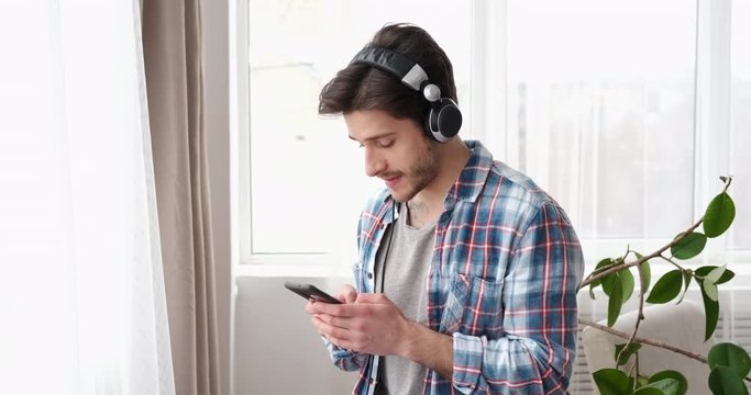 Man using mobile phone and listening music on headphones
