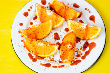 Orange slices with chilli powder and chamoy on colorful background